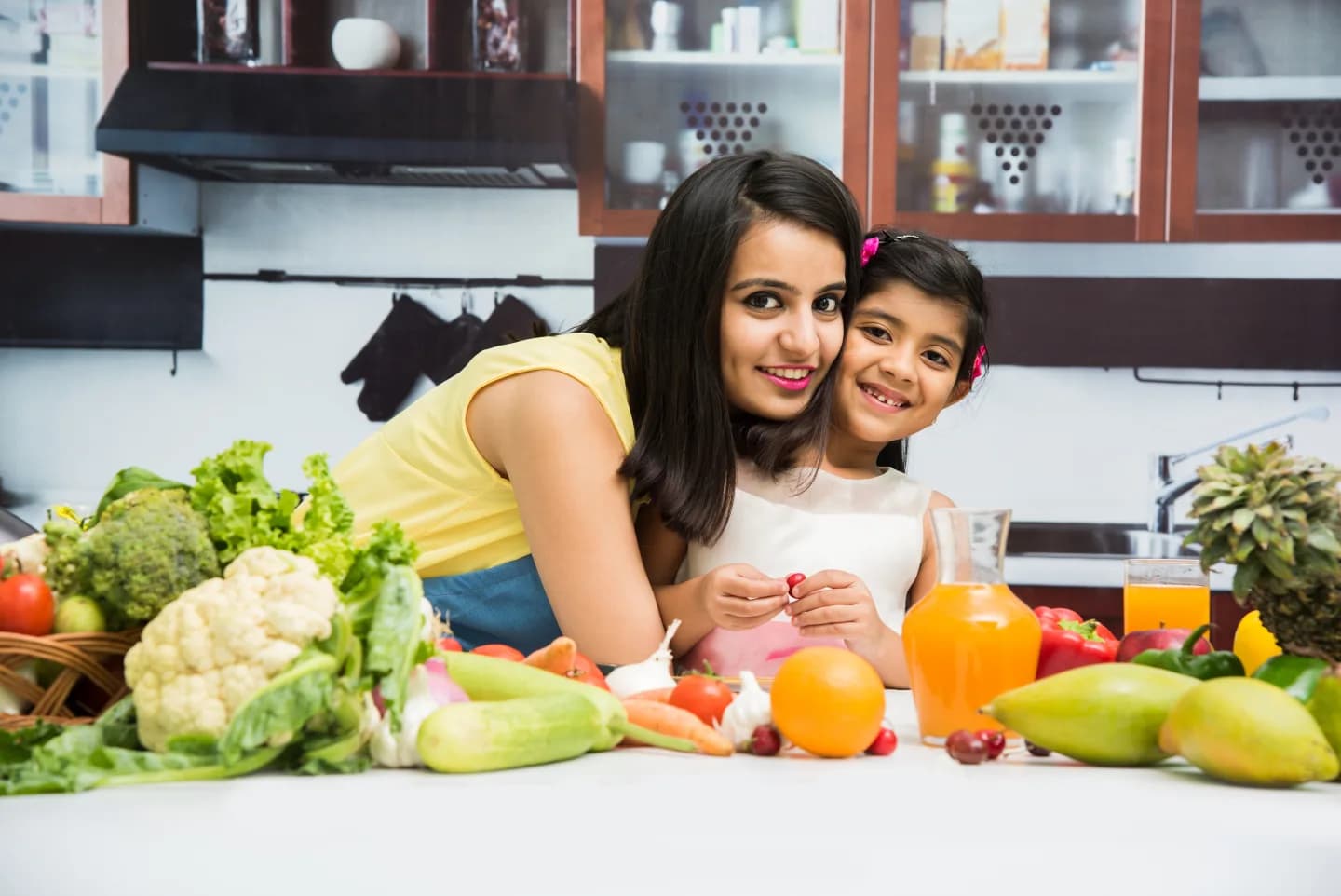 A mother and daughter in a kitchen surrounded by fresh ingredients